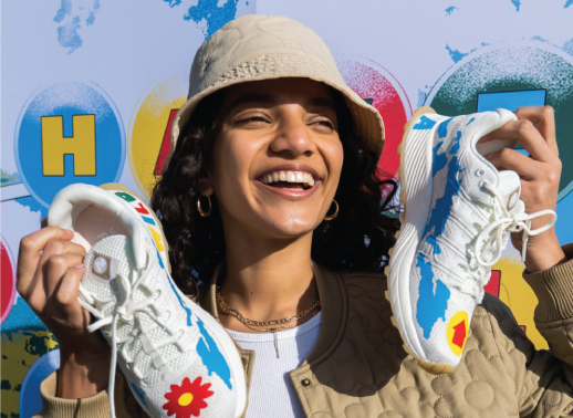 woman holding two merrell know your code trainers